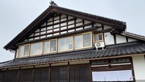 A traditional Japanese building with a tiled roof, wooden beams, and large sliding doors.