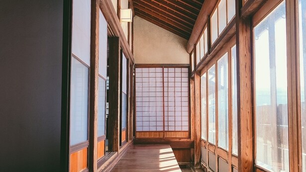 A traditional Japanese room with tatami flooring, sliding shoji doors, and wooden beams.