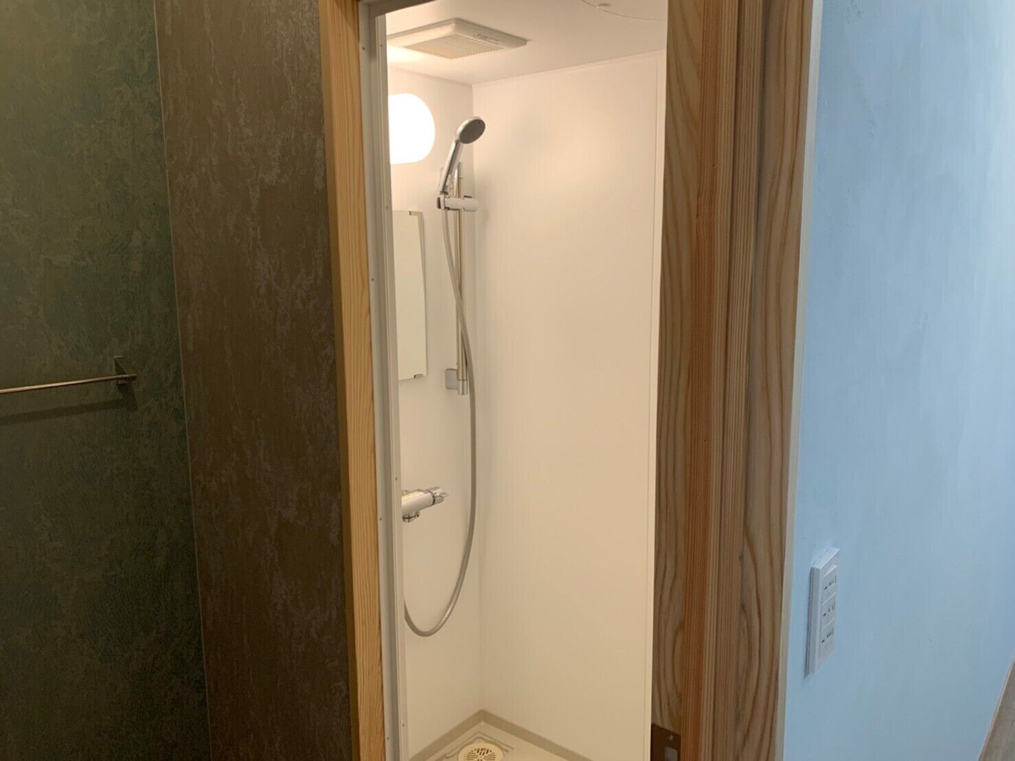 Une petite salle de bain étroite, équipée d’une douche, d’un porte-serviettes et de toilettes.