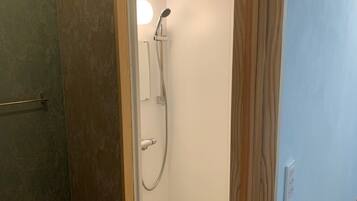 Une petite salle de bain étroite, équipée d’une douche, d’un porte-serviettes et de toilettes.