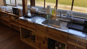 A kitchen with a stainless steel sink, wooden cabinets, and a window with a view of a green field.