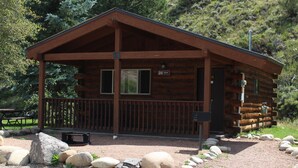 A rustic cabin with a porch, a picnic table, and a sign indicating room number 24. - One Bedroom Cabin with Ample Parking and Space from Neighboring Cabins (Almont)