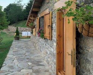 Un bâtiment en pierre avec des volets en bois et un chemin de pierre menant à l’entrée.