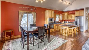 Una cocina amplia con armarios de madera, una isla central con taburetes y un comedor con mesa y sillas.