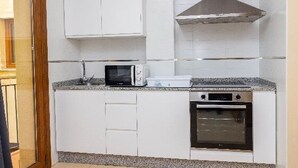 Una cocina con armarios blancos, microondas, estufa y horno.
