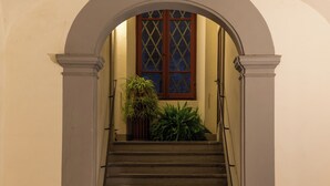 Una escalera con un arco blanco, barandal de madera y una ventana con diseño de celosía.