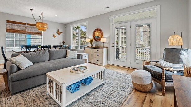 Un salon spacieux avec un canapé gris, une table basse blanche et un coin repas comprenant une table et des chaises.