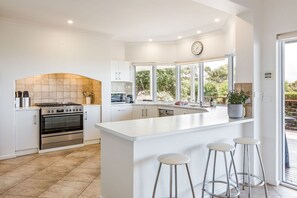 Una cocina moderna con armarios blancos, horno empotrado y una isla grande con taburetes de bar.