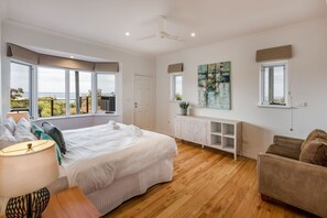 Un dormitorio con una cama grande, una mesita de noche, una lámpara, una ventana con vistas, un ventilador de techo y un armario.