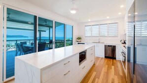 Una cucina moderna con una grande isola, mobili bianchi e vista sul mare.
