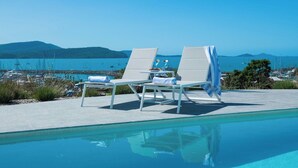 Zona piscina con lettini e vista sul mare.