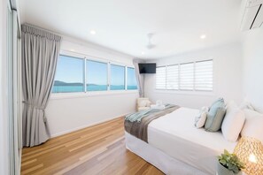 A bedroom with a bed, a TV, and a view of the sea. - Airlie On Airlie Premier (Airlie Beach)