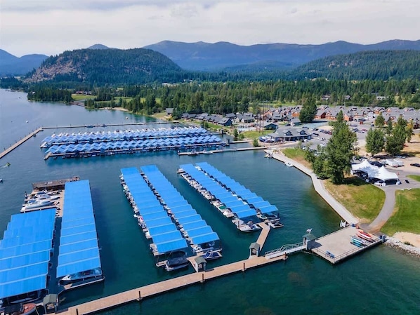 Une vue aérienne d’une marina avec de nombreux quais, des bateaux et une petite ville en arrière-plan.