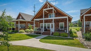 A modern two-story house with a prominent wooden facade, large windows, and a covered front porch. - Dover Bay 'Barefoot Bungalow' | Marina + Trails (Dover)
