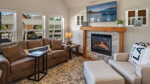 A cozy living room with a fireplace, leather sofas, and a view of a lake. - Dover Bay 'Barefoot Bungalow' | Marina + Trails (Dover)