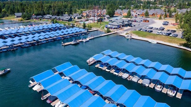 A marina with numerous boats docked under blue canopies, surrounded by residential buildings and mountains in the background. - Dover Bay 'Barefoot Bungalow' | Marina + Trails (Dover)