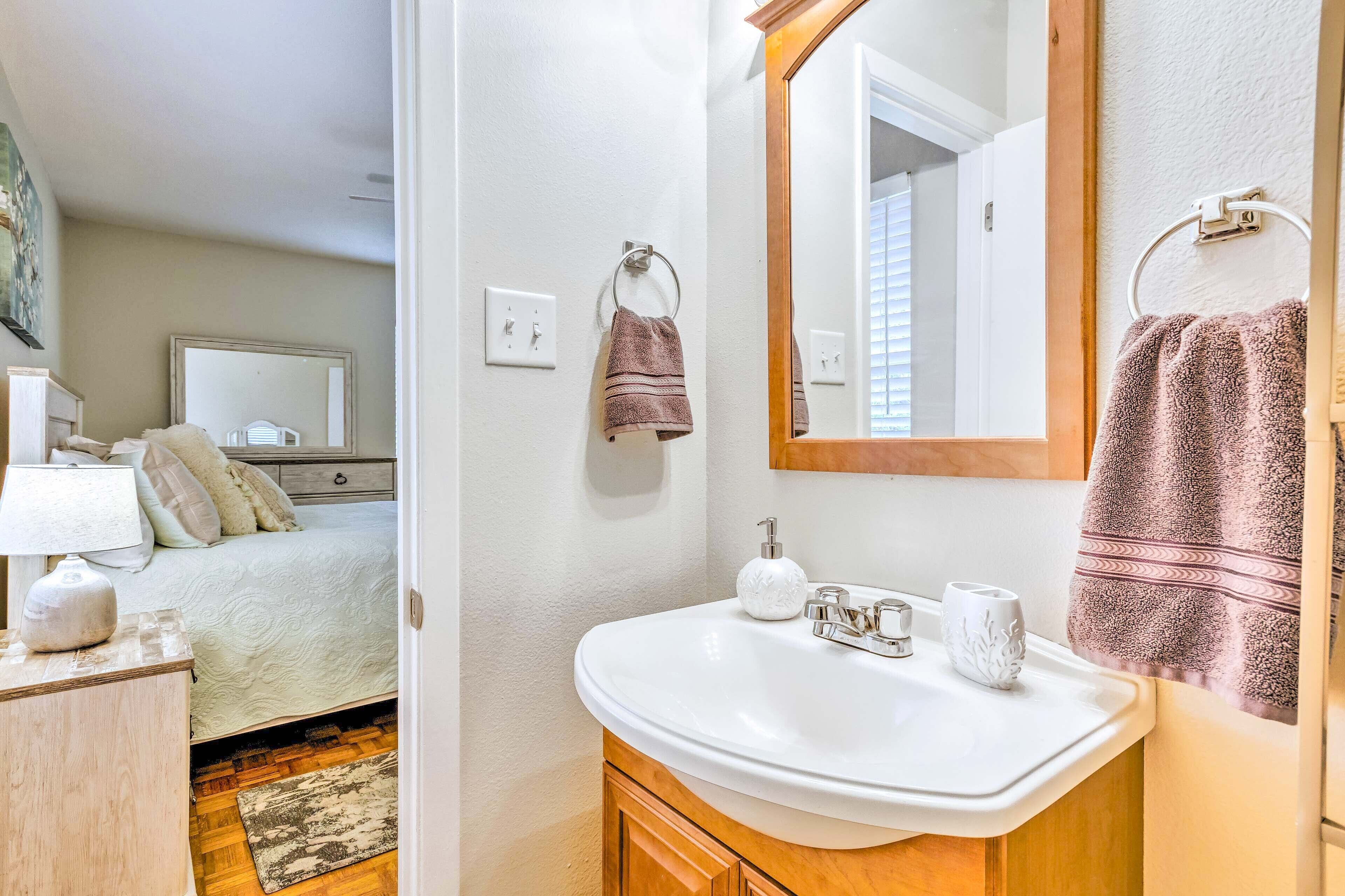 A bathroom with a white sink, a mirror, and a towel hanging on the wall.