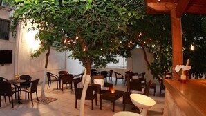 Un espace extérieur aménagé avec des tables et des chaises, un arbre et un comptoir de bar.