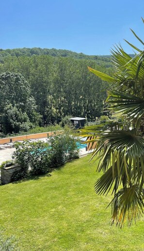 Un espace piscine avec vue sur une colline boisée.