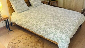 A bedroom with a bed, a nightstand, a lamp, a green vase, and a window with curtains. - Gîte le grand chacel (Sourcieux-les-Mines)