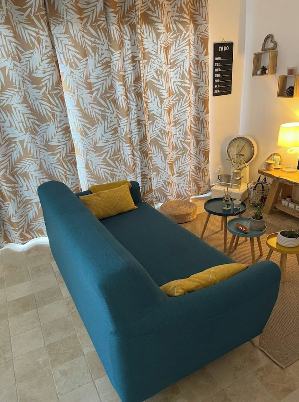 A living room with a blue sofa, a small round table, a lamp, and a wall with a 'To Do' list.