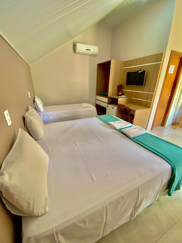 Un dormitorio con dos camas, televisión, armario y escritorio.