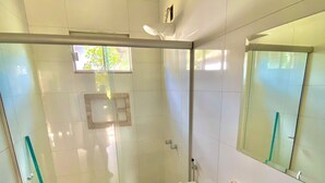 A modern bathroom with a glass shower enclosure, a toilet, and a sink with a marble countertop. - Pousada Beira da Mata (Mateiros)