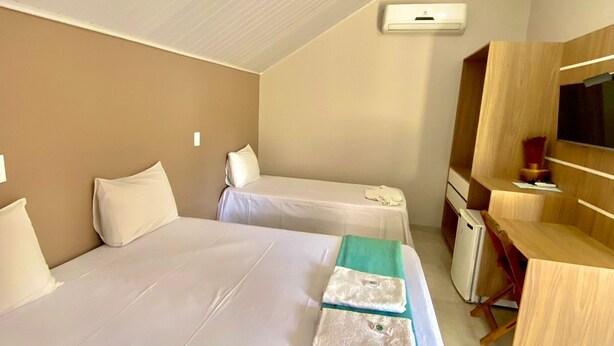 A hotel room with two beds, a desk, a mirror, and a TV. - Pousada Beira da Mata (Mateiros)