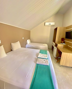 Habitación de hotel con dos camas, un escritorio, un espejo y un televisor.