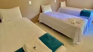 A hotel room with two single beds, a teal accent pillow, and a white blanket on one bed. - Pousada Beira da Mata (Mateiros)