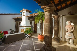 Experience the tranquil atmosphere of our serene courtyard, surrounded by stone columns and a tiled roof, featuring a traditional statue and lush greenery.
