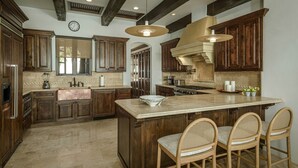 A spacious kitchen with dark wooden cabinets, a large island, and a modern pendant light.