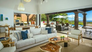 A spacious living area with a large sofa, wooden coffee table, and a view of the outdoors.