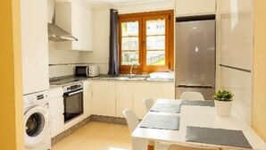 Eine kleine Küche mit Waschmaschine, Mikrowelle und Edelstahlkühlschrank.