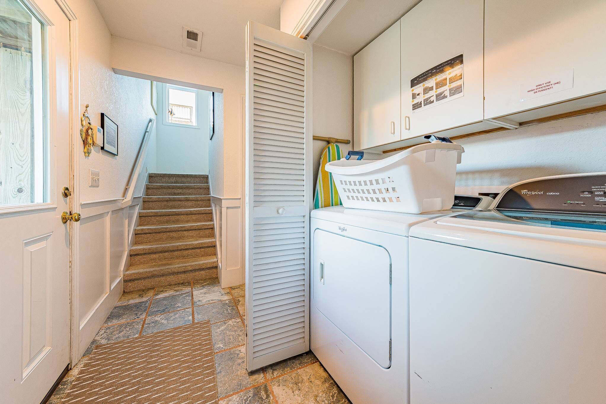 A laundry room with a washing machine, a dryer, and a wall-mounted cabinet.