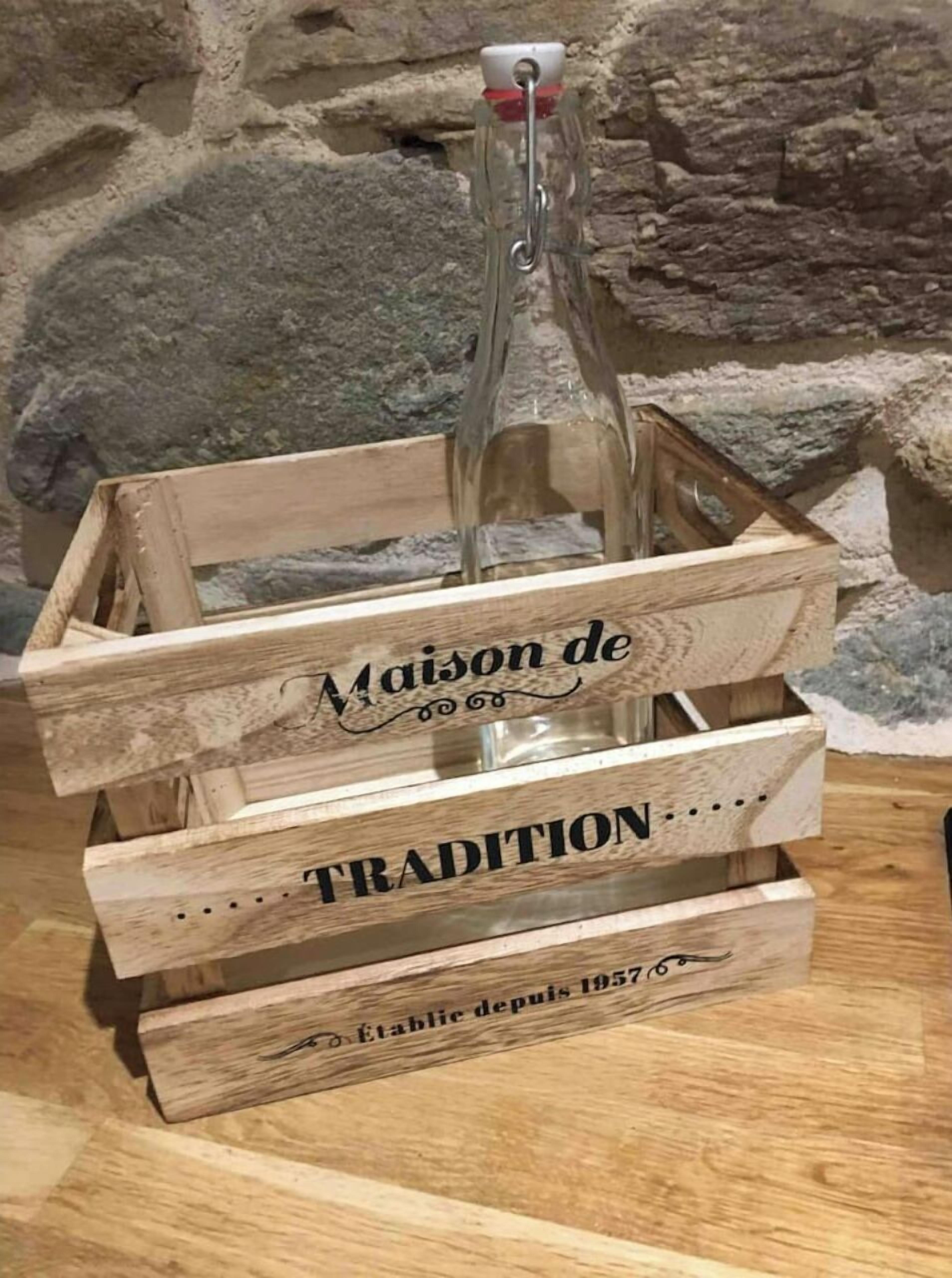 Een houten kist met een fles wijn, voorzien van de tekst 'Maison de TRADITION' en 'Établie depuis 1957'.