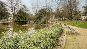 Ein Park mit Teich, Bänken und Bäumen.