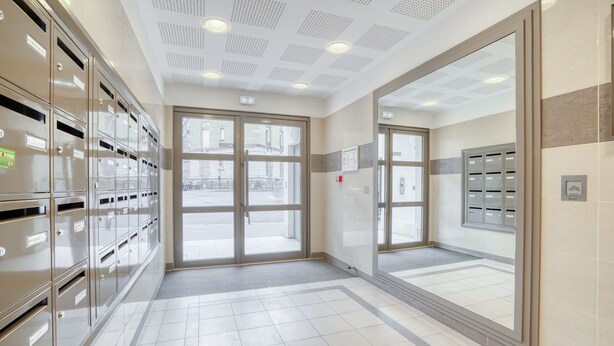 Eine saubere, moderne Lobby mit Metallschließfächern, großen Fenstern und einem gefliesten Boden.