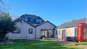 A house with a large lawn, a swimming pool, and a red telephone booth. - Laighdykes Guest Cottage 2 Bedroom & Gym Saltcoats (Saltcoats)
