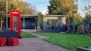 A red telephone booth, a modern building with large windows, and a well-maintained lawn. - Laighdykes Guest Cottage 2 Bedroom & Gym Saltcoats (Saltcoats)