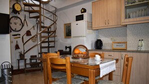 A kitchen with wooden cabinets, a spiral staircase, a dining table with chairs, and a clock on the wall. - Ethia 2floor Mountain View Cottage Garden Wifi ac (Archanes-Asterousia)