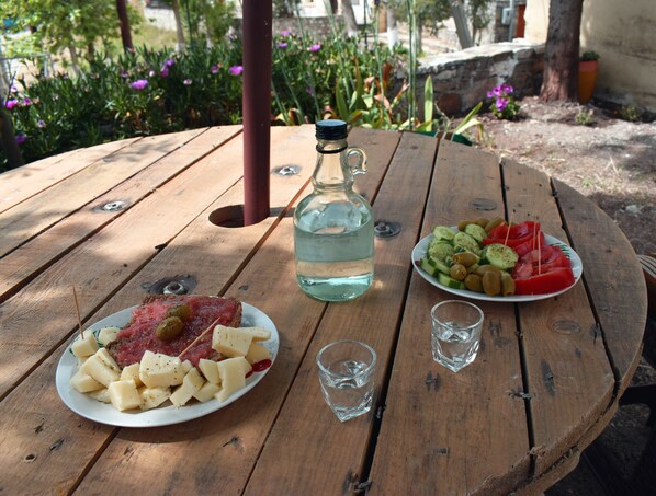 Una mesa de madera con un plato de comida, una botella de agua y dos vasos.