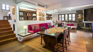 Una sala de estar moderna con una escalera de madera, un sofá rojo, una mesa de comedor con sillas y una chimenea.