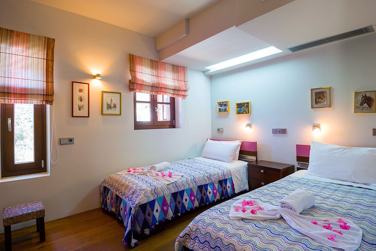 A hotel room with two beds, a bench, and wall-mounted artwork.