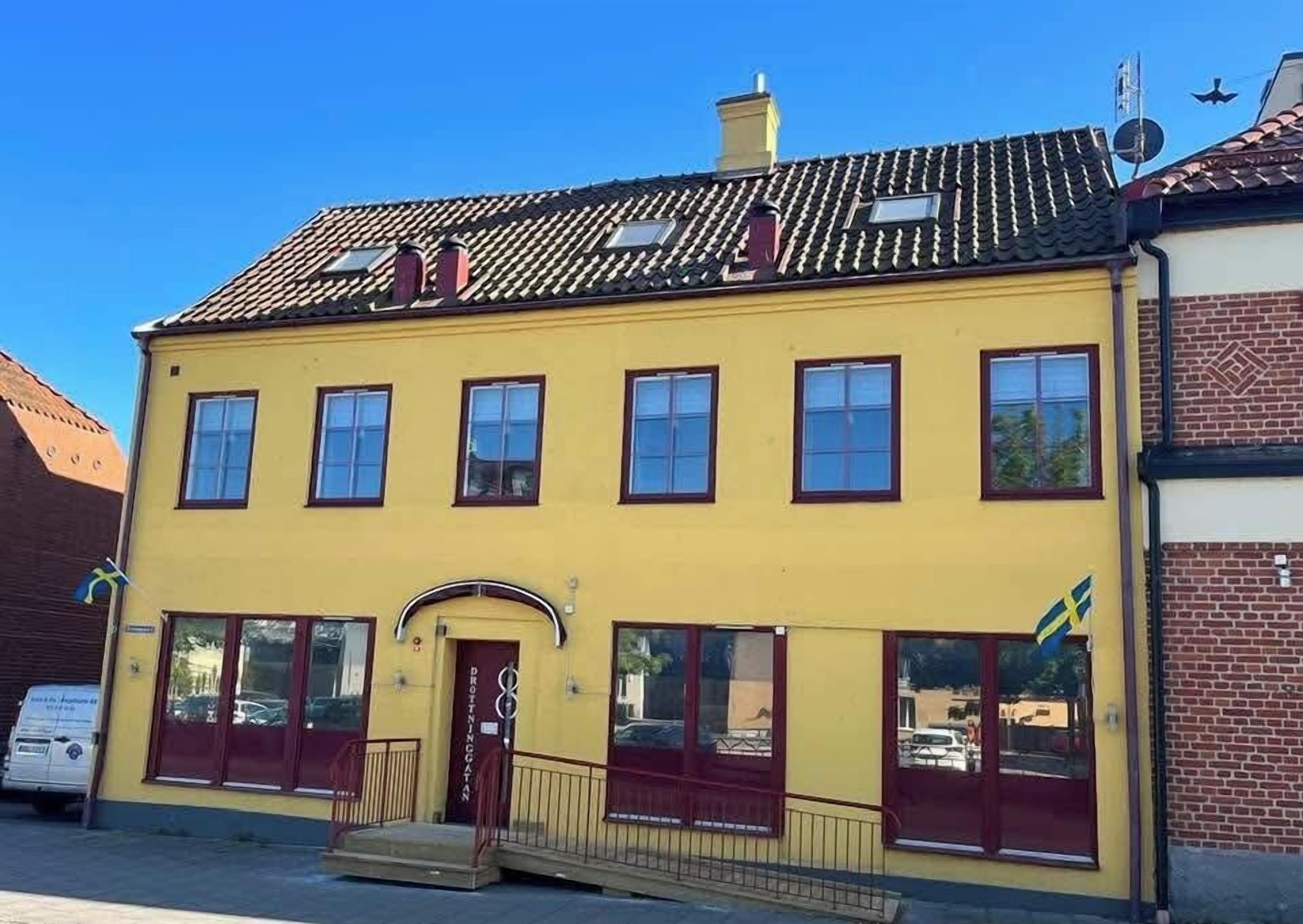 A yellow building with a red door and multiple windows.