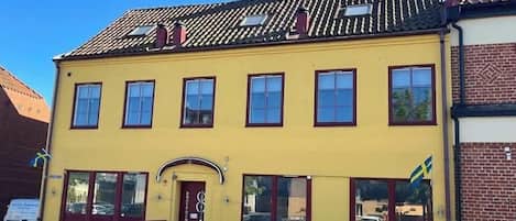 A yellow building with a red door and multiple windows.
