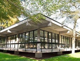 Un edificio moderno con techo plano, ventanas amplias y estructura de hormigón.
