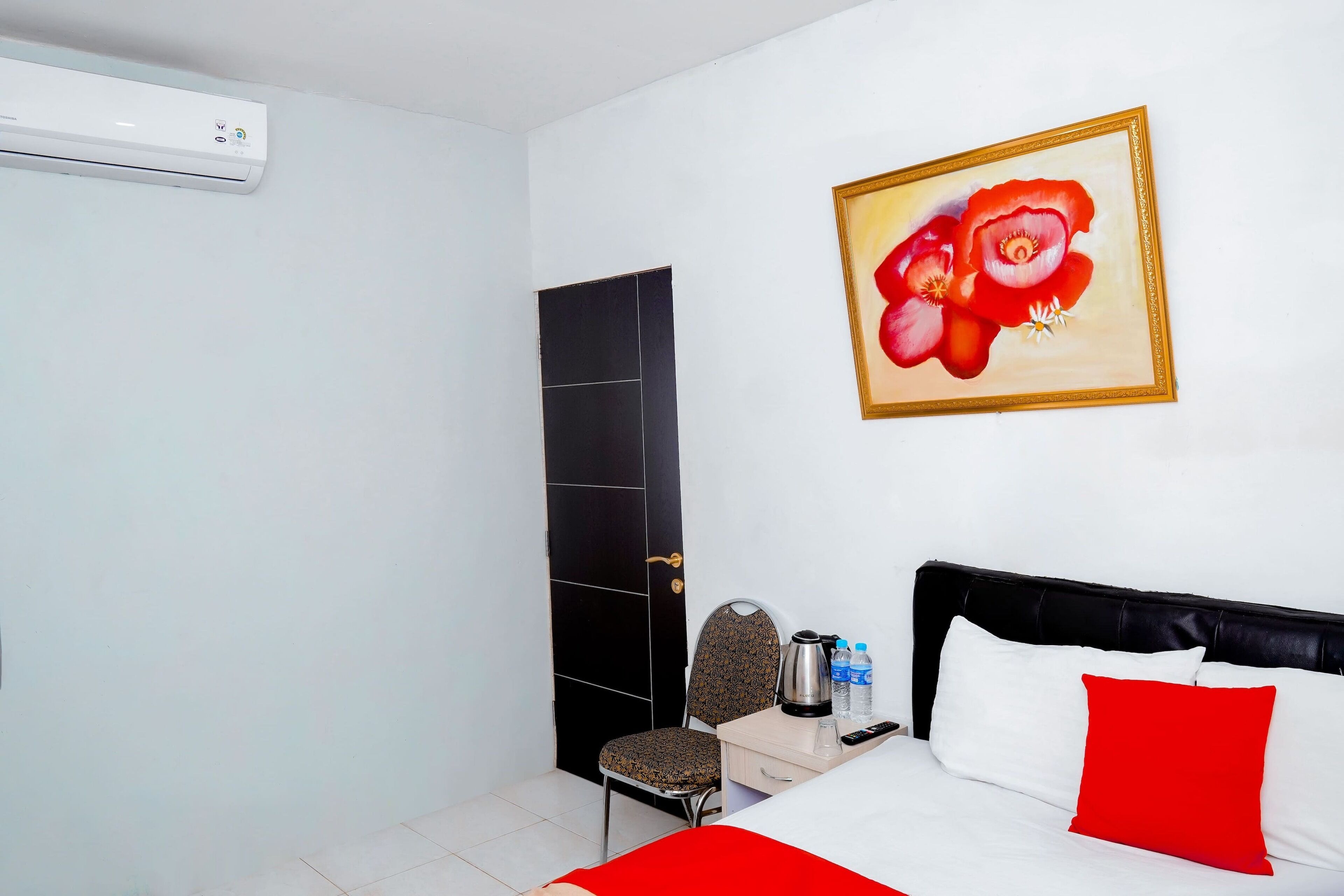 Una habitación de hotel con cama, una silla, un escritorio y un cuadro en la pared.