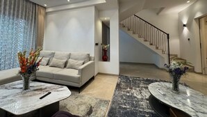 Un salon moderne avec un canapé, deux tables en marbre et un escalier.