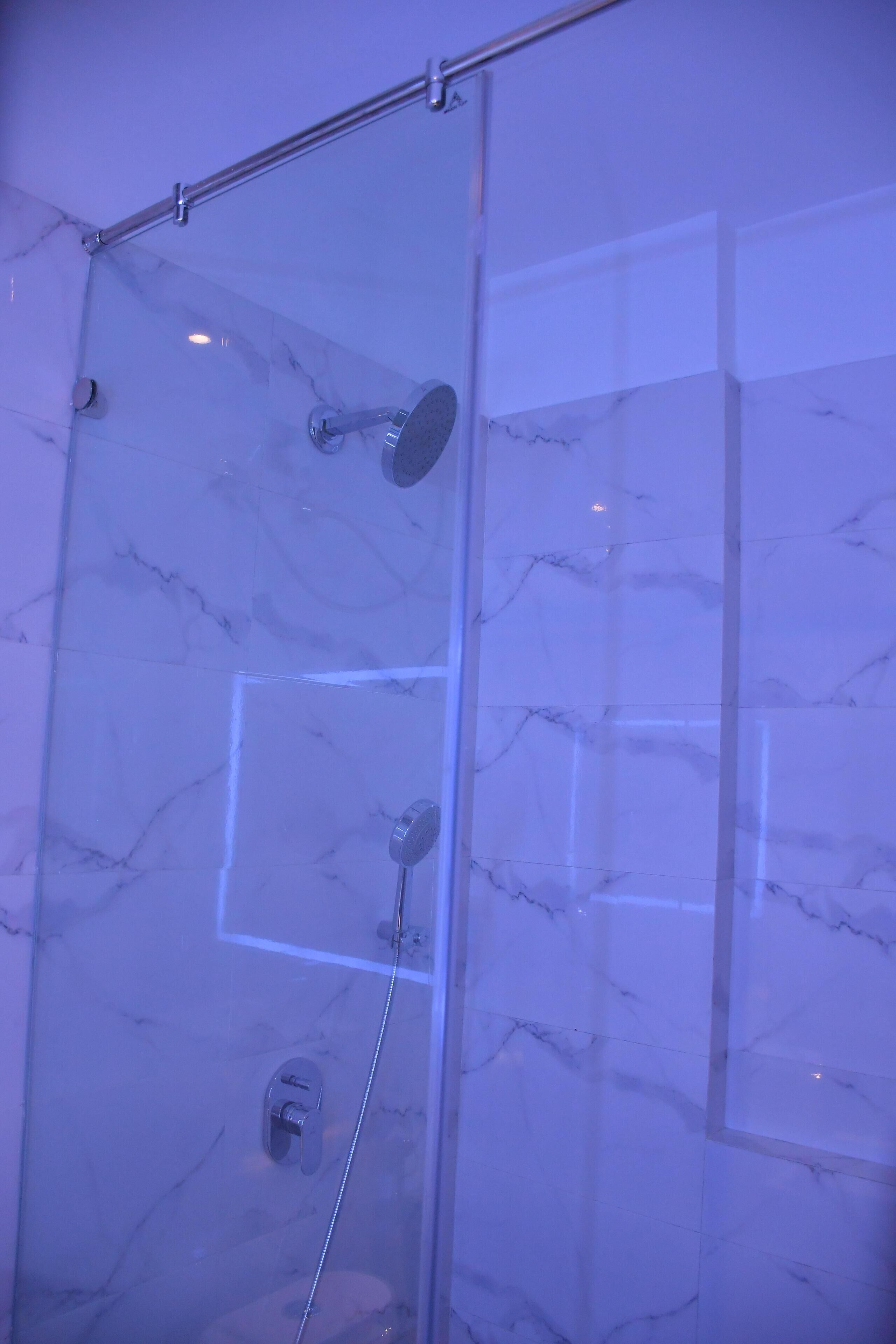 Eine Duschkabine mit Handbrause und am Wand montiertem Wasserhahn.
